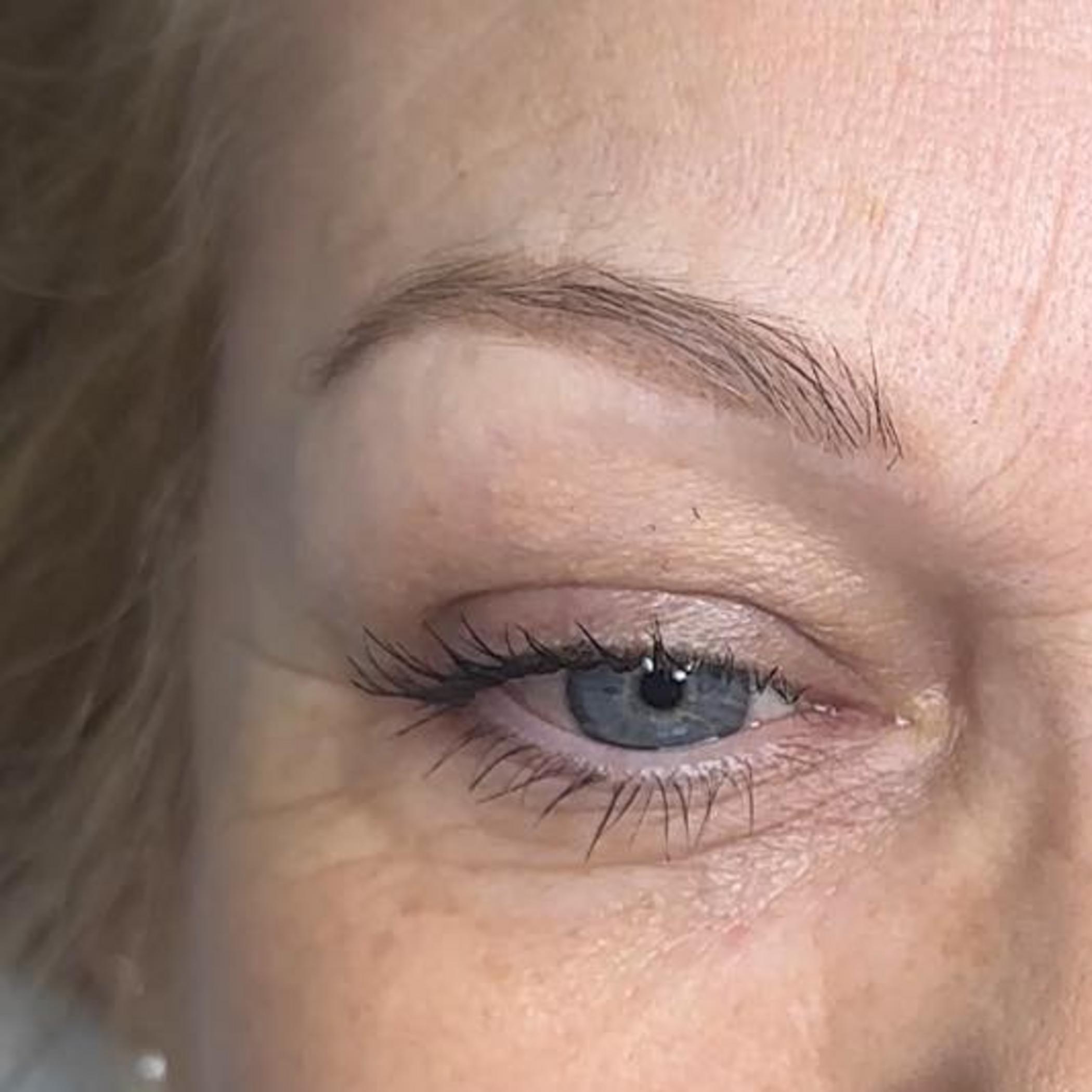 technician applying microblading eyebrow strokes