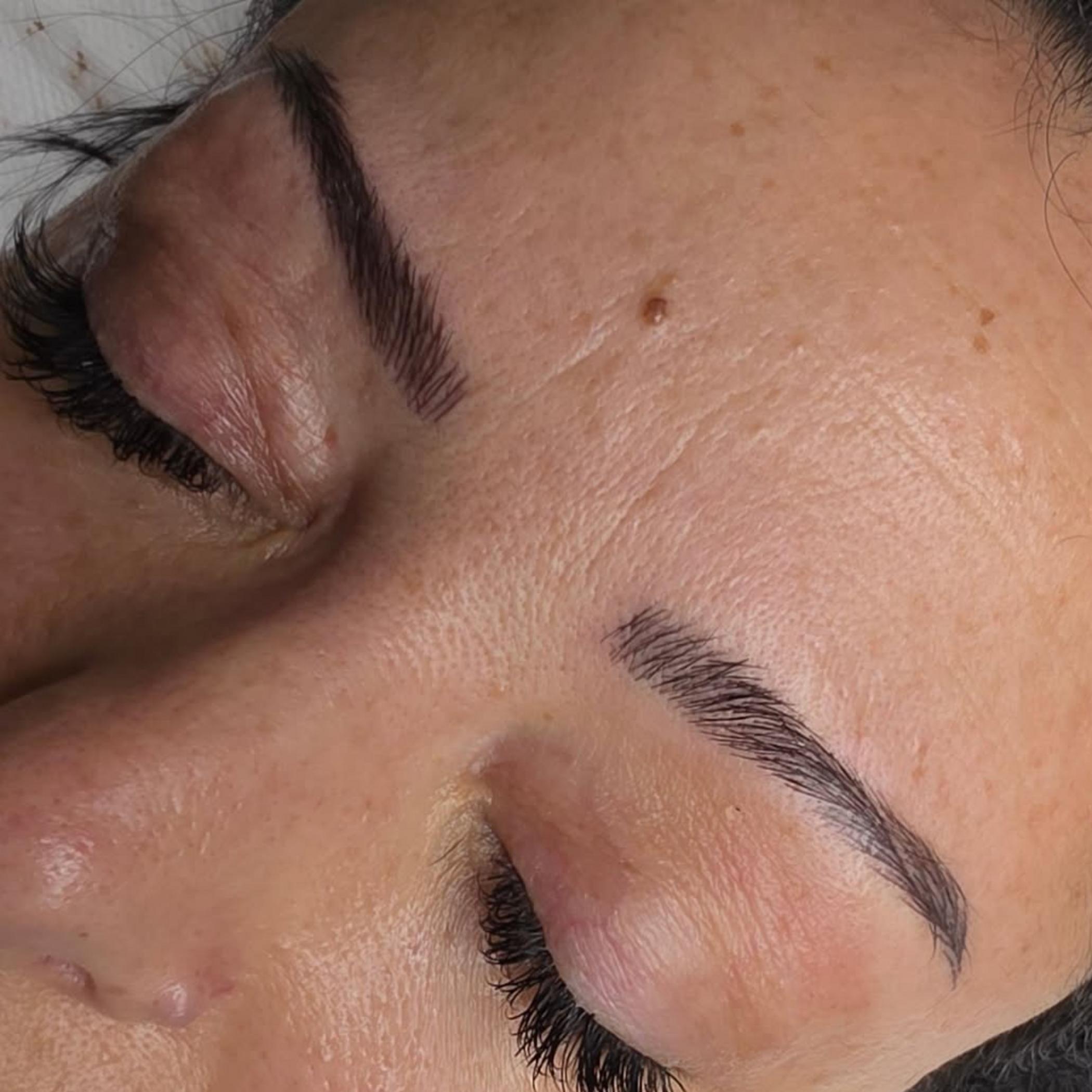 technician shaping brows with pencil guide